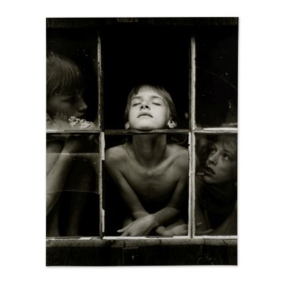 photographie en noir et blanc représentant trois enfants regardant par la fenêtre