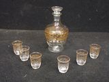 six glasses and a decanter sitting on a table