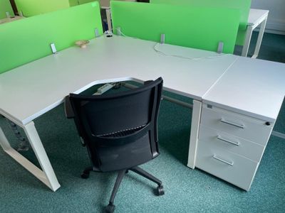 a white desk with a black chair and a green divider