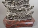 statue of a man sitting on a rock with a leaf in his hand