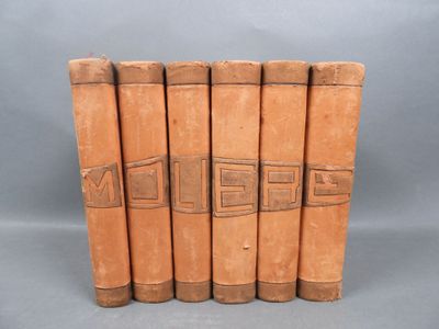 six old leather books lined up in a row on a gray background
