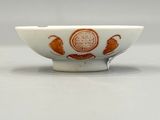 an orange and white bowl sitting on top of a white table