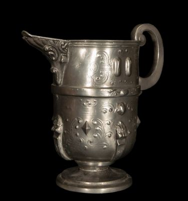 un vase en argent muni d'une anse, sur fond noir
