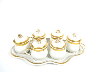 a tray with five white and gold teapots on it