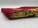 red and gold embroidered book with gold trim on a white surface