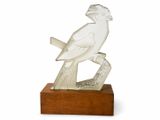 sculpture représentant un oiseau perché sur une branche, posée sur un socle en bois