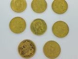 six types différents de pièces d'or sur une surface blanche