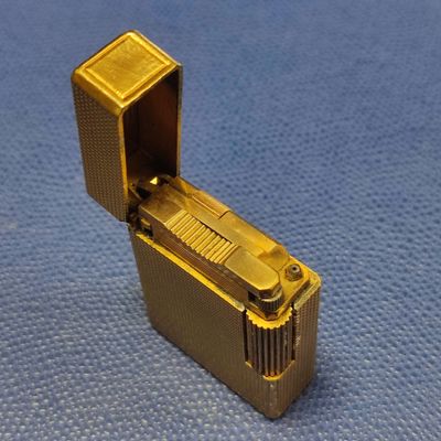 a gold lighter that is sitting on a blue surface