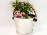a metal bucket with flowers in it on a white surface