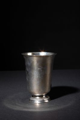 a silver cup sitting on a table with a black background