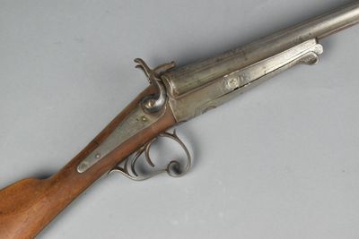 un vieux pistolet avec une poignée en bois sur une surface blanche