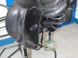 une selle noire posée sur un support dans une pièce bleue
