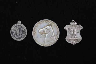 trois médailles d'argent sur une surface noire, sur fond noir