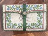 un petit sac à main orné d'un ruban vert et de fleurs bleues