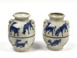 une paire de vases bleus et blancs ornés de chevaux sur un fond blanc
