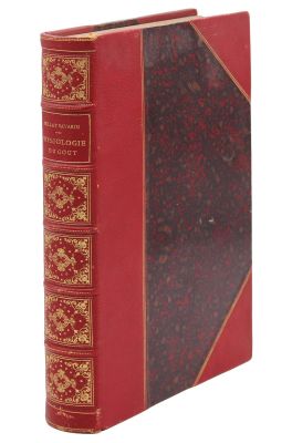 un vieux livre à la couverture rouge posé sur une surface blanche