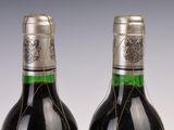 two bottles of red wine with a silver cap on top of them