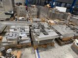 many pieces of metal in a warehouse with pallets on the floor