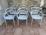 six white plastic chairs sitting in front of a stone wall