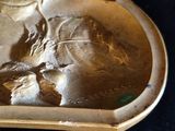 a gold plate with a picture of a woman and a bird on it