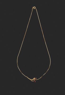 un collier en or avec un oiseau suspendu à une chaîne, sur fond noir