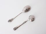 two spoons that are sitting on a white surface