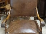 brown leather chair sitting in front of a wooden cabinet in a room