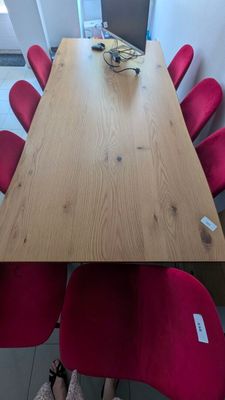 une longue table avec des chaises rouges et un ordinateur portable posé dessus