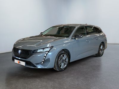 Une voiture grise est garée dans une pièce aux murs blancs.