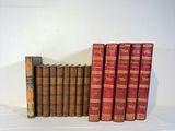 several old books are lined up on a shelf in front of a white wall