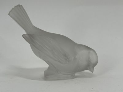 a glass bird that is sitting on a white surface