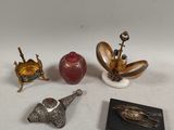 four silver and gold figurines of various shapes and sizes on a white surface