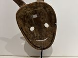 an image of a wooden mask on a stand on a white surface