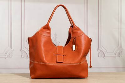 a brown leather handbag sitting on top of a wooden table
