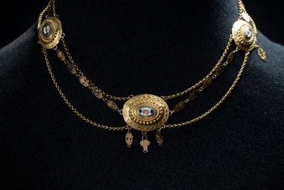 un gros plan sur un mannequin portant un collier en or orné d'un œil bleu