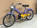 une moto violette et jaune garée contre un mur