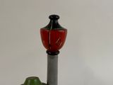 a red and black vase sitting on top of a metal pole