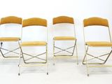 quatre chaises pliantes disposées côte à côte sur un sol blanc