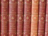 several old books are lined up on a shelf in front of a white wall