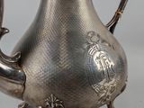 a silver tea pot with a handle on a table