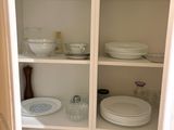 a white cupboard with dishes and plates on it