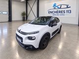 une Citrole blanche garée dans un garage, avec une grande enseigne en arrière-plan
