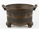 un bol ancien en bronze muni d'anses, sur fond blanc