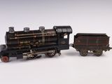 un petit train miniature posé sur une surface blanche, à côté d'un autre plus petit