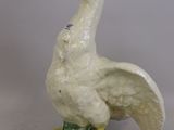 une image représentant une statue de canard blanche et jaune posée sur un socle vert