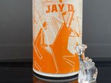 bougeoir en céramique orange et blanche, orné d'une figurine en cristal posée sur un fond noir