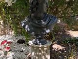 a statue of a man sitting on a pedestal in a garden