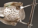 a silver bird that is hanging on a wire