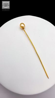 a white plate with a gold plated pin on it