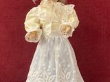 une poupée ancienne en porcelaine représentant une jeune fille vêtue d'une robe blanche et d'une jupe bleue